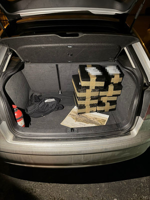 widać wagę, narkotyki w woreczku foliowym i zgrzewnicę. białe kryształki w worku foliowym, następnie dłoń w gumowej rękawiczce przekłada worki z marihuaną w kartonie. radiowóz, policjanta, który zakłada kajdanki zatrzymanemu, który leży na ziemi, następnie widok na pomieszczenie, w którym są paczki i worki z narkotykami, leżący luźno susz i półki na których są różne przedmioty. W pomieszczeniu panuje rozgardiasz.