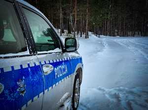 Bok policyjnego radiowozu i widoczny dookoła śnieg.