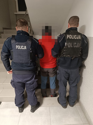Dwaj policjanci prowadzą zatrzymanego.