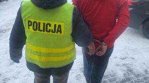 Policjant prowadzi zatrzymanego.