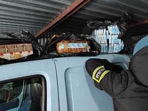 Zabezpieczone przez policjantów papierosy w paczkach na dachu samochodu. Obok stoi funkcjonariusz.