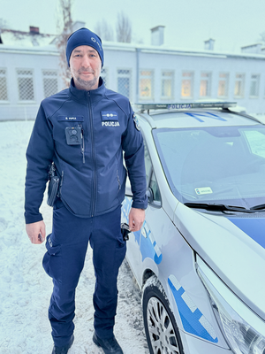 Policjant stoi przy radiowozie.