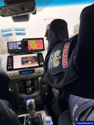 Policyjny radiowóz od środka i widoczne rękawy polskiego i holenderskiego policjanta.