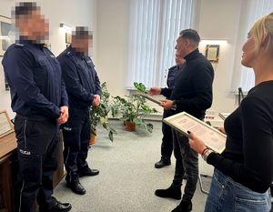 Policjanci stoją w gabinecie. Otrzymali podziękowania.