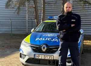 Policjant stoi przy radiowozie.