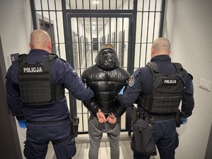 dwóch policjantów prowadzi zatrzymanego.