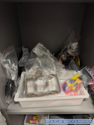 W otwartej skrytce foliowe kolorowe opakowania zawierające środki odurzające.