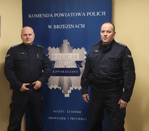Dzielnicowi, policjanci stoją na tle napisu Policja.