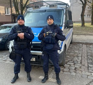 policjanci stoją przy radiowozie.
