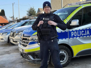 Umundurowany policjant przy radiowozie.