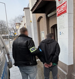 Policjant prowadzi zatrzymanego.