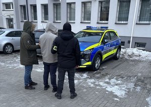 zatrzymany przez policję stoi przy radiowozie.
