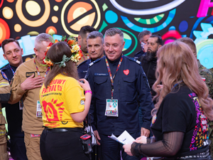 Zastępca komendanta głównego Policji razem z policjantami w studiu finału WOŚP wśród innych ludzi.