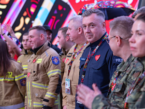 Zastępca komendanta głównego Policji w studiu Finału WOŚP wśród funkcjonariuszy Straży Pożarnej i Straży Granicznej.