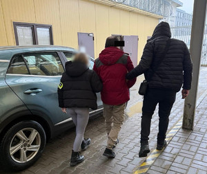 dwóch policjantów prowadzi zatrzymanego.