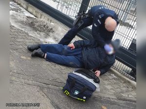 policjant pomaga mężczyźnie, który leży na ziemi.