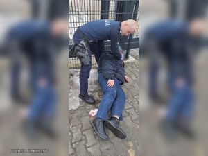 policjant pomaga mężczyźnie, który leży na ziemi.