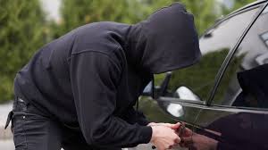 Mężczyzna w kapturze włamuje się do auta - zdjęcie poglądowe.