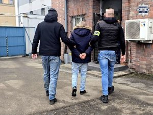 Dwaj nieumundurowani policjanci prowadzą zatrzymanego.