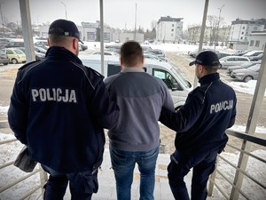 Dwaj policjanci prowadzą zatrzymanego.