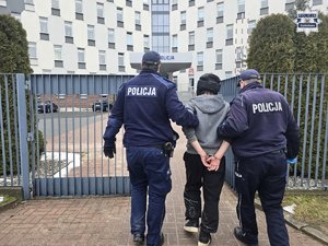 Dwaj policjanci prowadzą zatrzymanego.