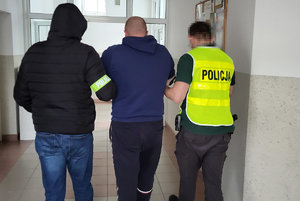 dwóch policjantów prowadzi zatrzymanego.