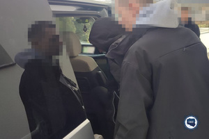 Policjant z zatrzymanym w trakcie wsiadania do samochodu.