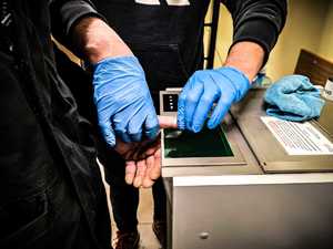 Policjant pobiera odciski palców od zatrzymanego.