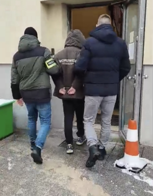 Dwaj policjanci prowadzą zatrzymanego.