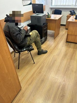 Na zdjęciu mężczyzna siedzi na krześle.