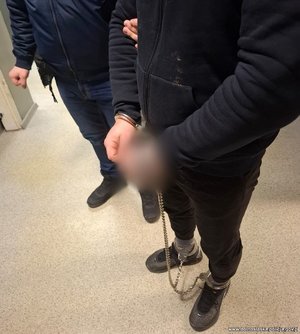 Zatrzymany mężczyzna zakuty w kajdanki zespolone.