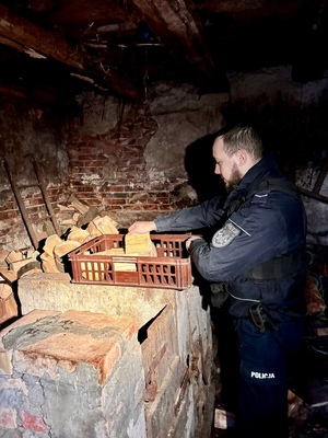 Policjant układa drewno.