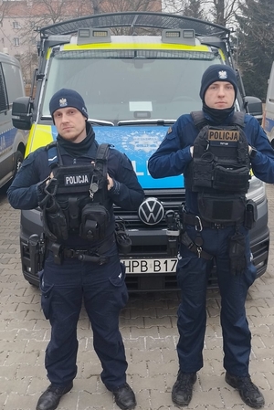 Dwaj policjanci przed radiowozem.