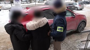 Policjanci prowadzą zatrzymaną.