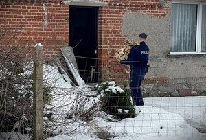policjant nosi drewno na opał.