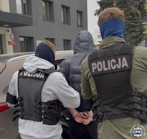 Dwóch nieumundurowanych policjantów prowadzi zatrzymanego.