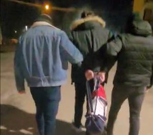 Dwaj funkcjonariusze prowadza zatrzymanego.