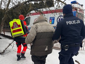 Policjanci i ratownicy medyczni prowadzą mężczyznę do karetki.