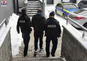 zima. policjanci prowadzą zatrzymanego mężczyznę.