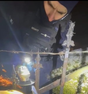 policjant tnie szlifierką kontową płot.