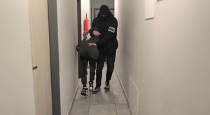 Policjant prowadzi zatrzymanego.