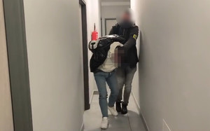 Policjant prowadzi zatrzymanego.