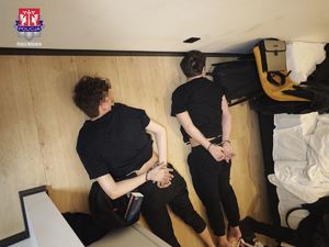 mężczyźni leżą na podłodze skuci kajdankami.