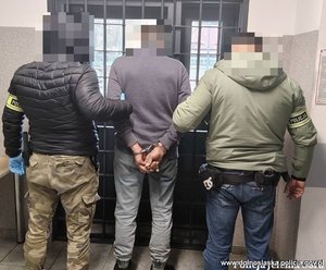 policjanci prowadza mężczyznę w kajdanach.