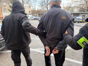 Dwaj policjanci prowadzą zatrzymanego.