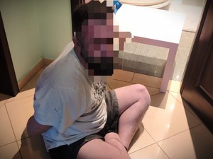 Zatrzymany mężczyzna siedzi na ziemi.