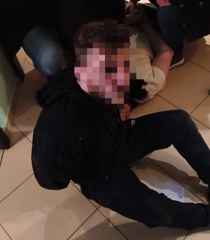 Zatrzymany mężczyzna siedzi na ziemi.