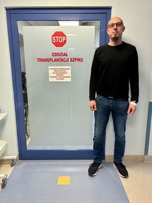 policjant stoi obok szpitalnych drzwi.