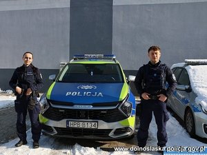 Dwaj policjanci przy radiowozie.