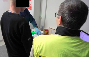 Policjant stoi obok mężczyzny.